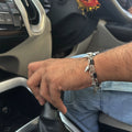 A close-up of a person's hand wearing a silver-toned chain bracelet with shark teeth and black accents on the wrist.