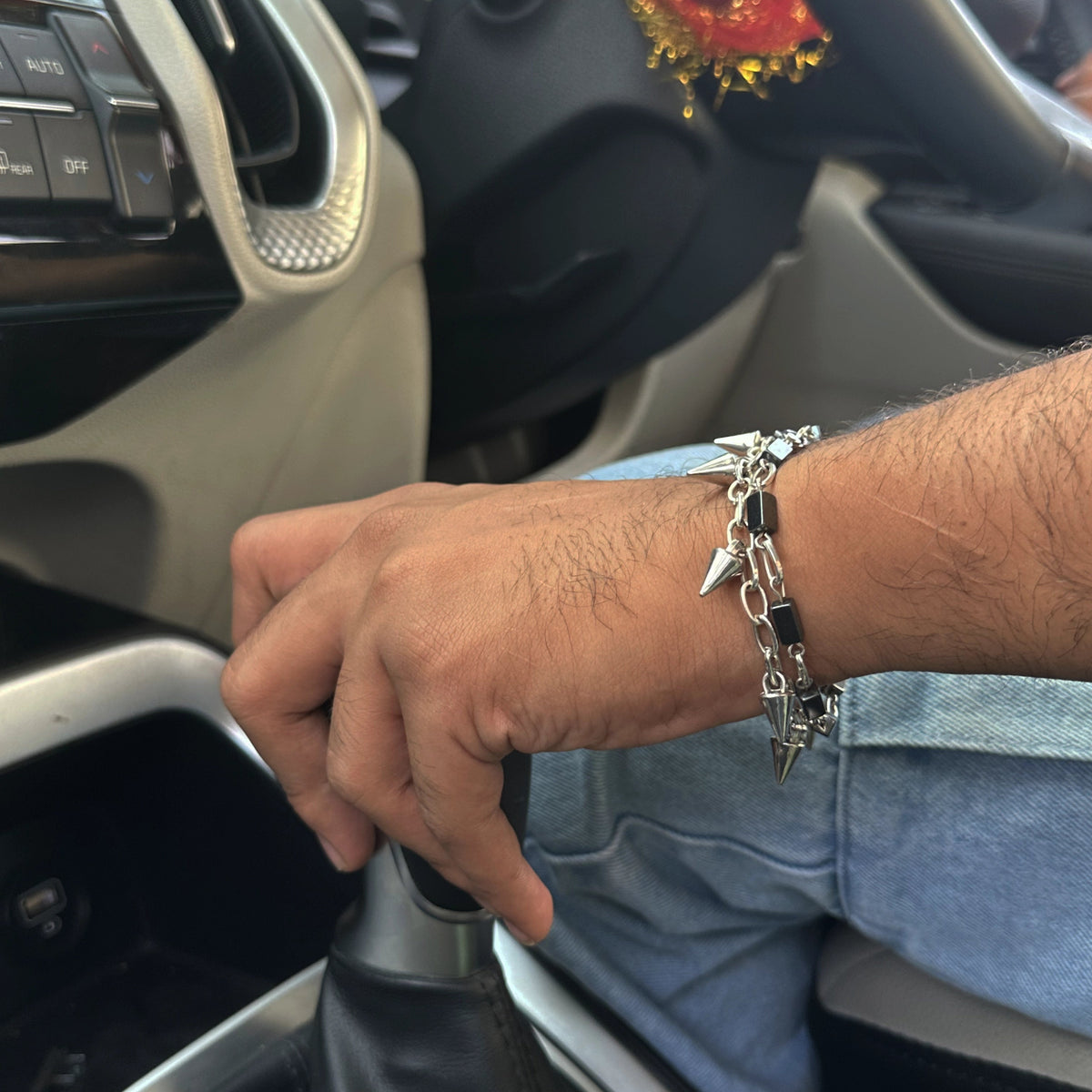 A close-up of a person's hand wearing a silver-toned chain bracelet with shark teeth and black accents on the wrist.