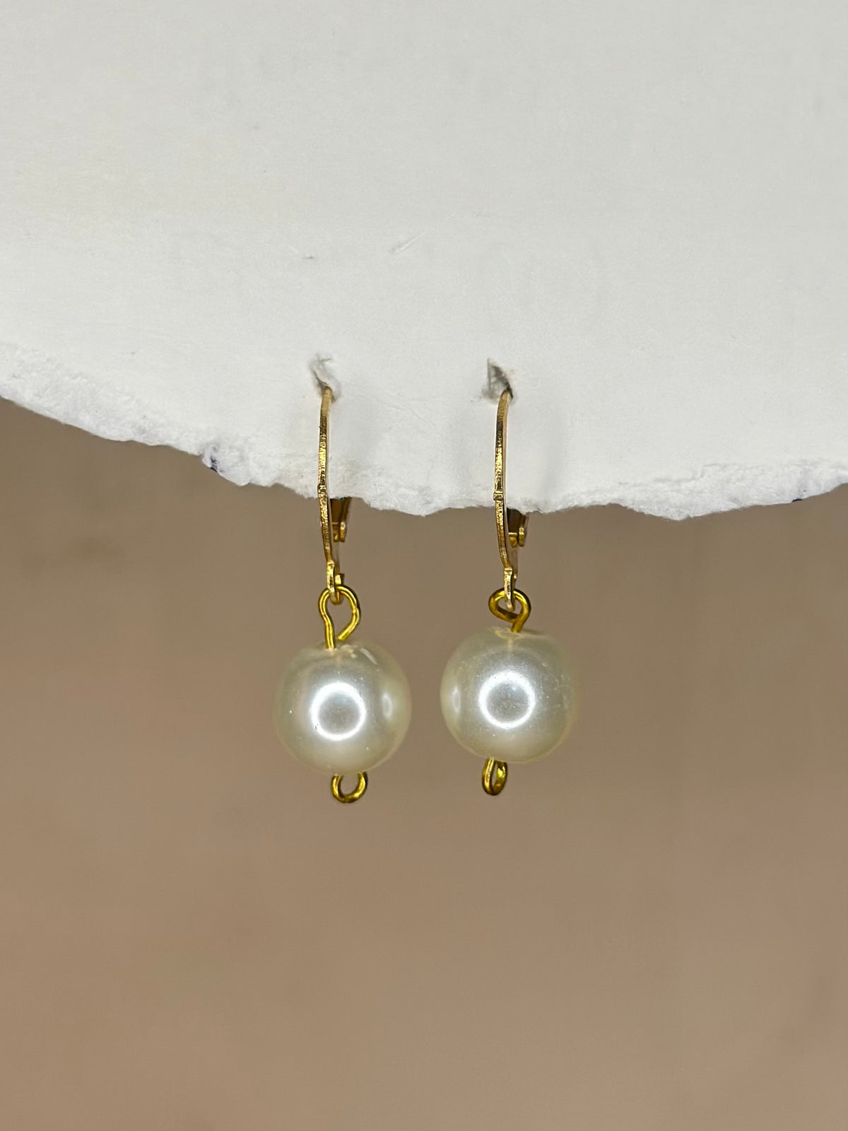 Handmade white pearl drop earrings with gold-tone hooks.
