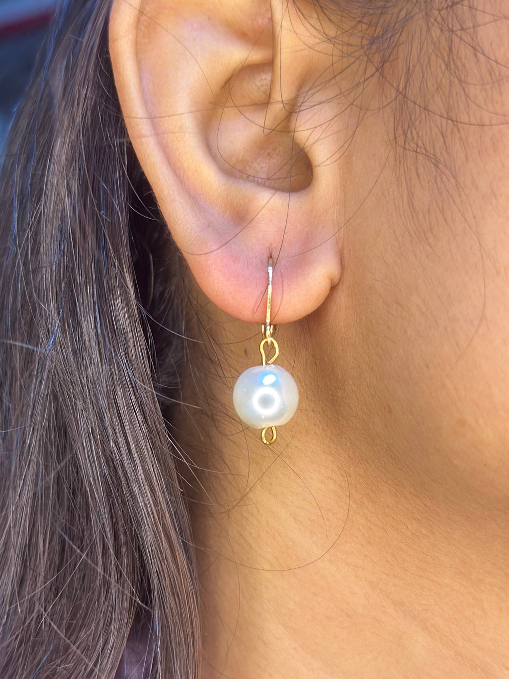 A close-up of a person's ear wearing a Handmade Pearl drop earring.