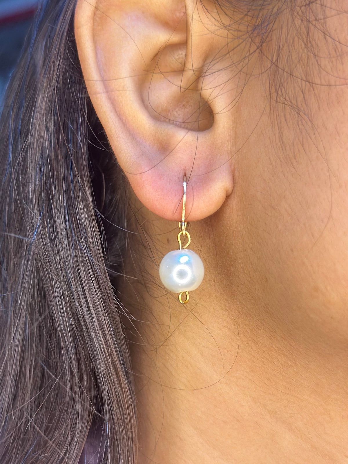 A close-up of a person's ear wearing a Handmade Pearl drop earring.