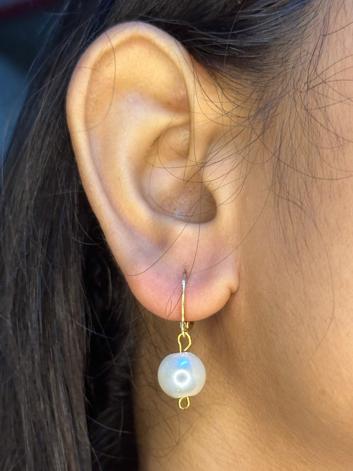 Close-up of a person wearing a handmade pearl drop earring.